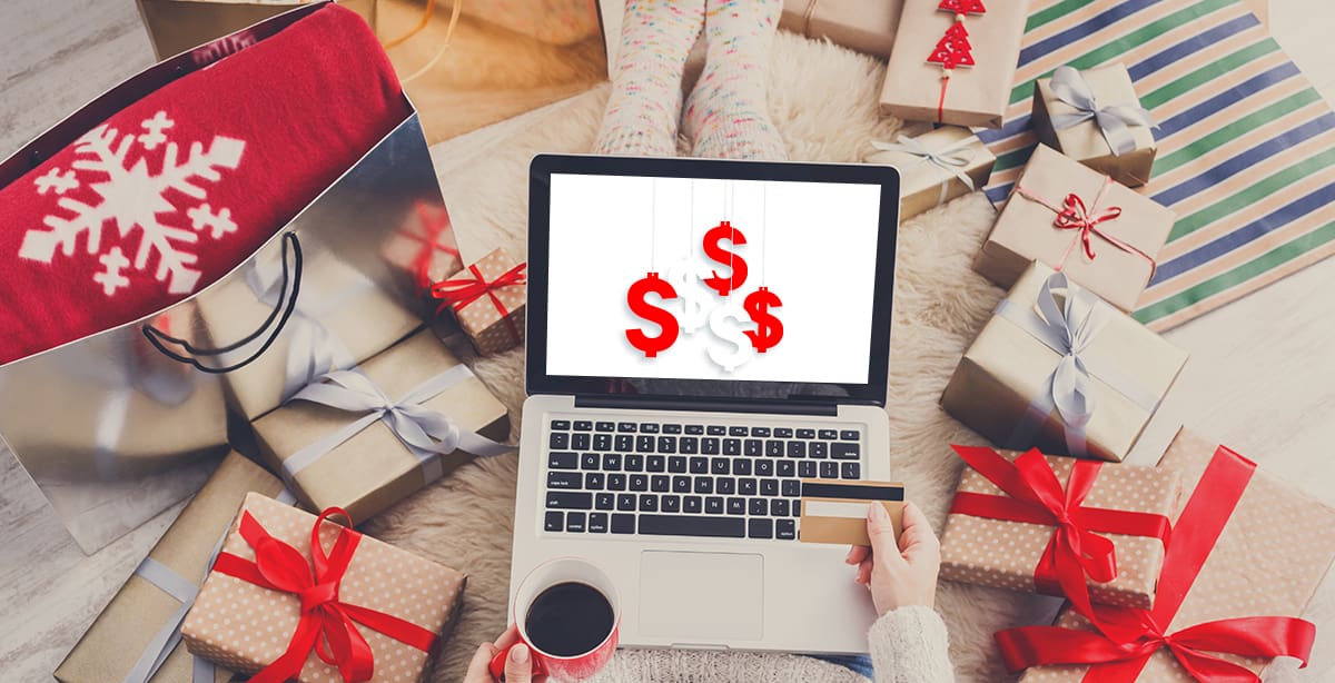 Computer with dollar signs on it surrounded by wrapped gifts