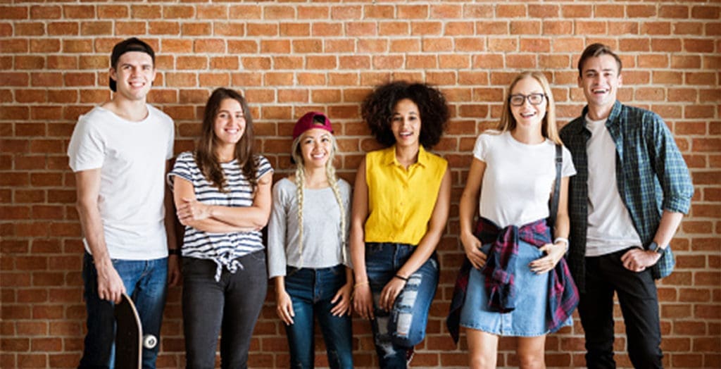 Young people standing against a wall, smiling