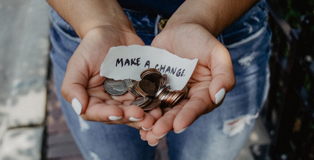 Woman holding change with a note saying, "Make a Change"