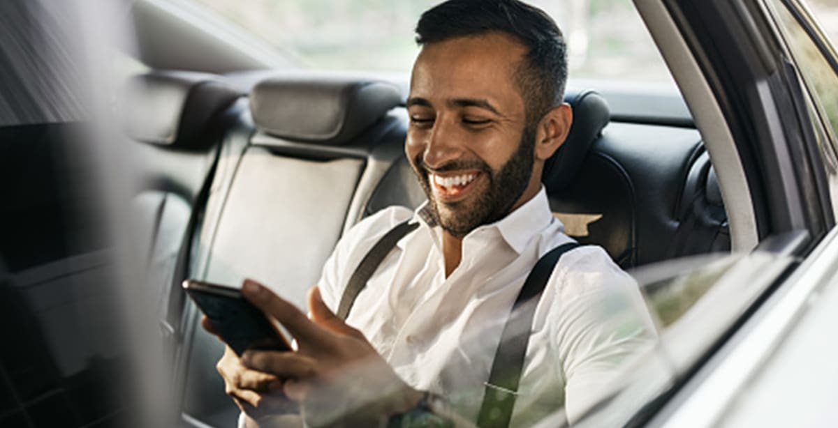 Man in the back of a car, smiling while on phone